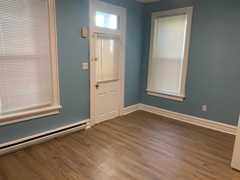 a room with a door and two windows and a wooden floor
