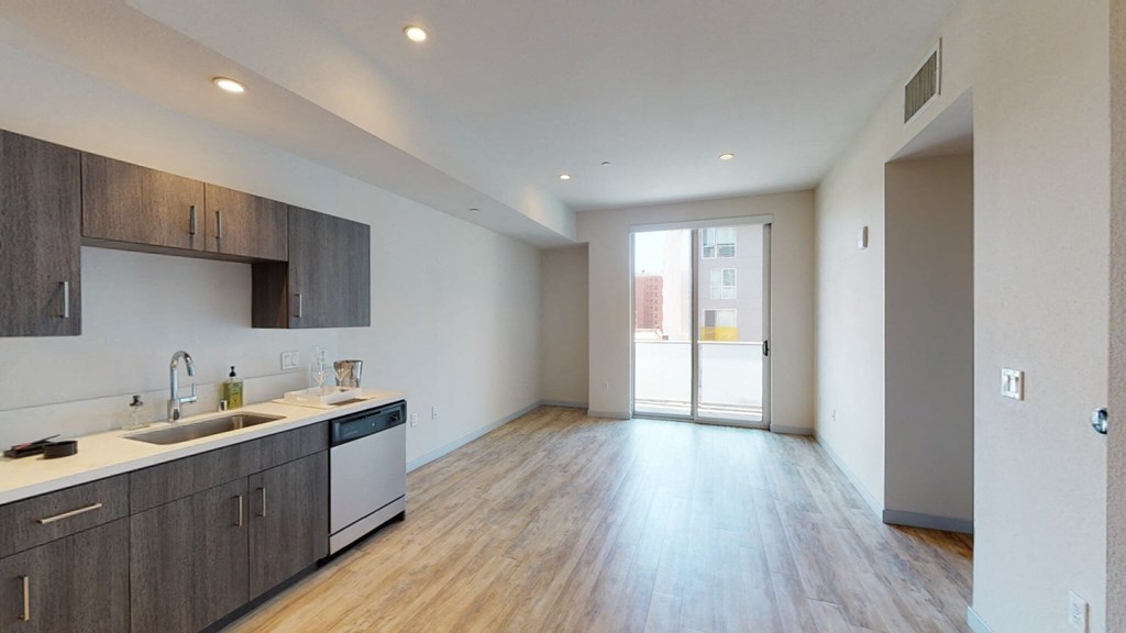 a kitchen and living room with wood flooring and a door to a balcony