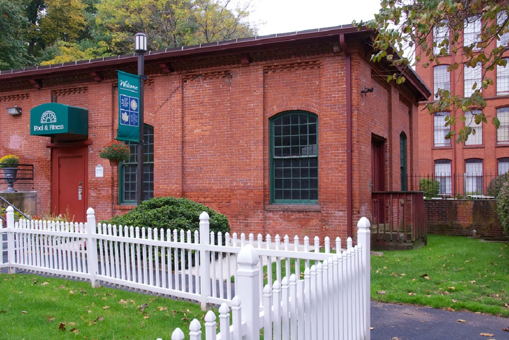 an old brick building with a white fence in front of it