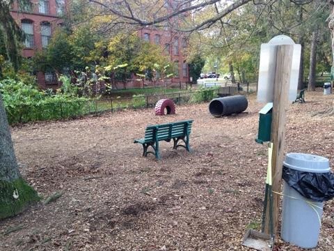a park bench and a garbage can in a park