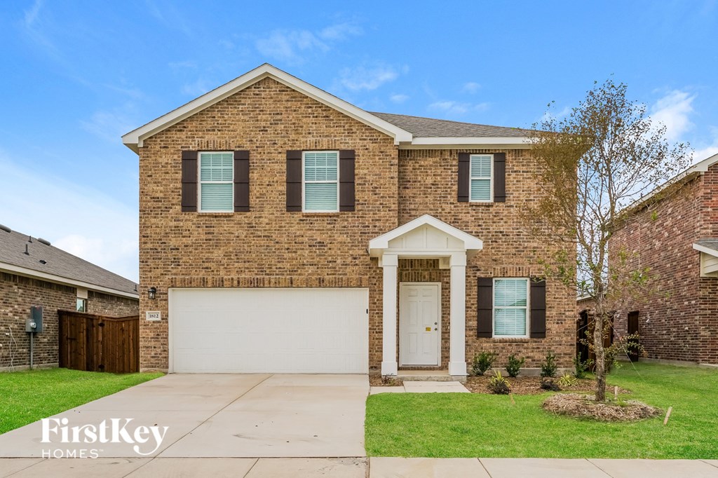 a brick house with a white garage door and a lawn