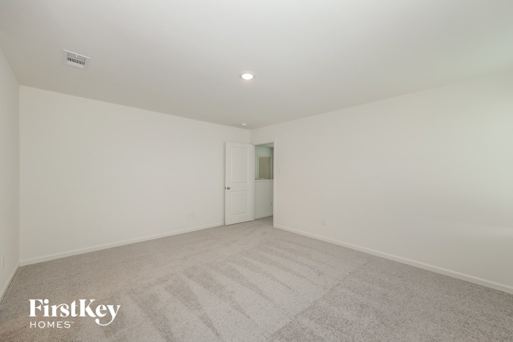 a bedroom with white walls and carpet and a door to a closet