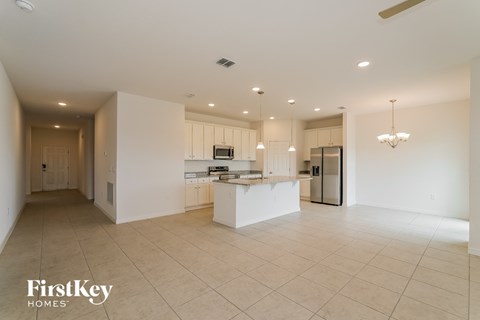 A spacious kitchen and living room with a television and a refrigerator.