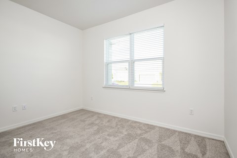 a bedroom with a window and white walls and carpet
