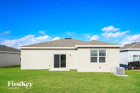 a beige house with a grass yard and a blue sky