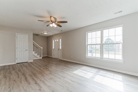 an empty living room with a ceiling fan and a window
