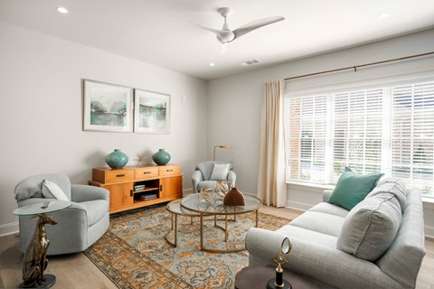 A living room with a grey couch, a wooden coffee table, and a ceiling fan.