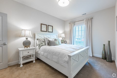 A white bedroom with a large bed and two lamps.