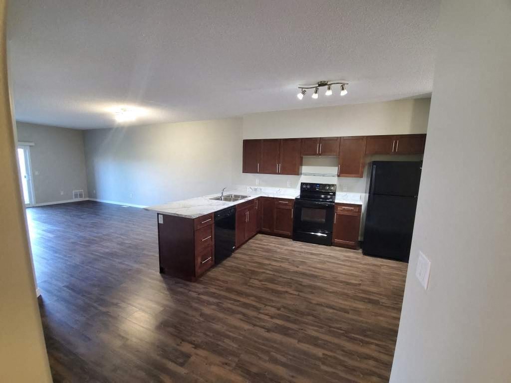 an empty kitchen and living room with wood flooring