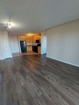 an empty living room with wooden floors and a kitchen