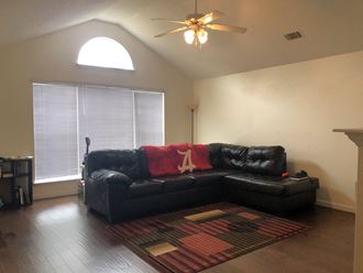 a living room with a black couch and a ceiling fan