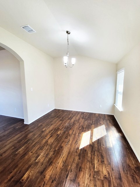 an empty living room with wood flooring and white walls