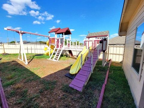 a playground with a playset and slides in a backyard