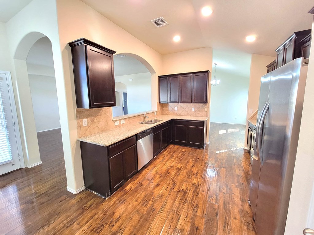 a kitchen with wooden floors and a stainless steel refrigerator