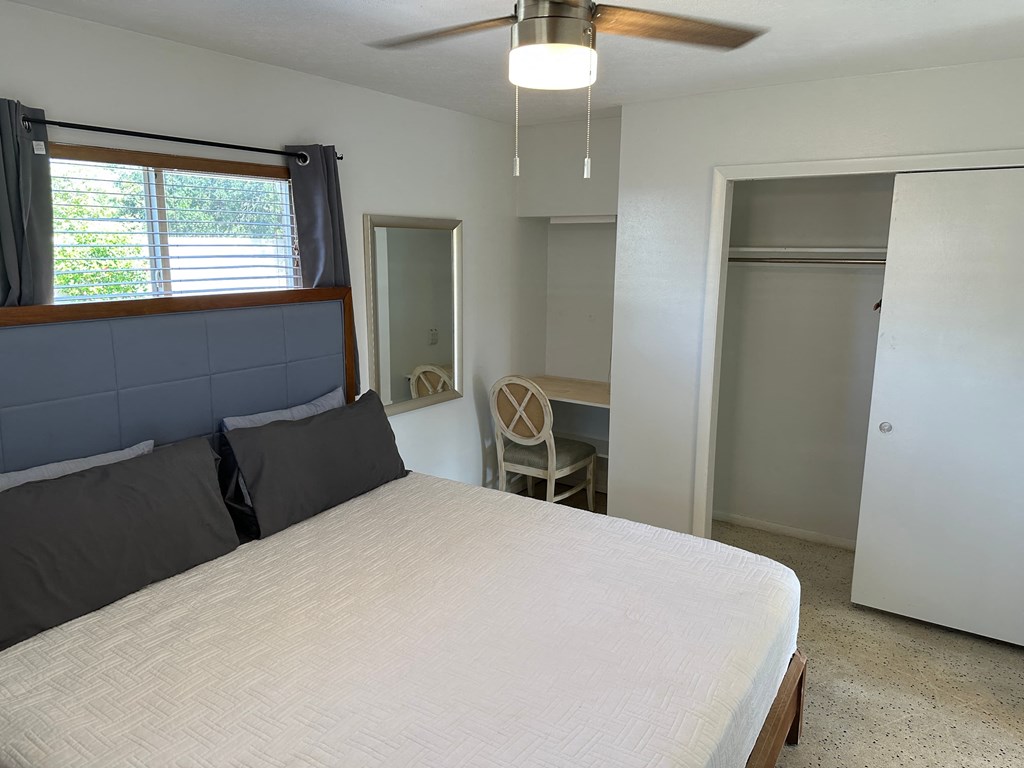 a bedroom with a bed and a desk and a ceiling fan
