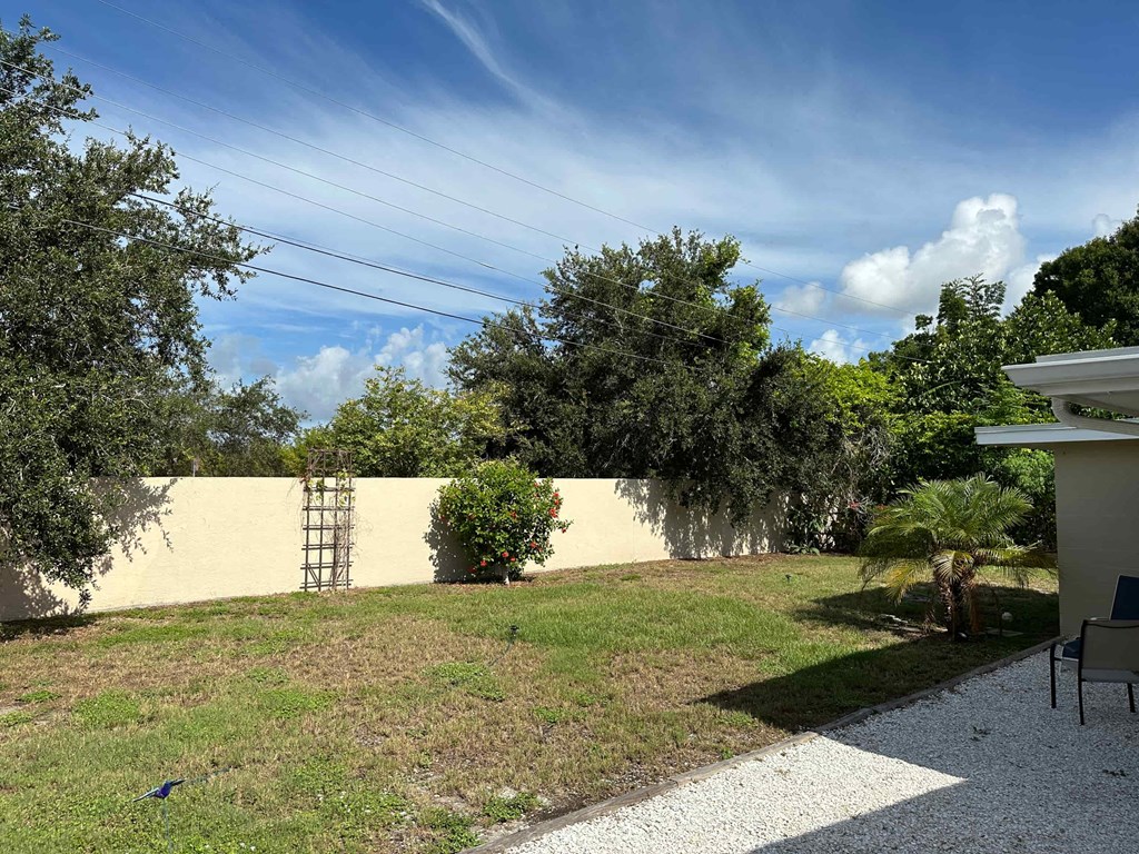 a backyard with a yellow wall and a lawn and trees