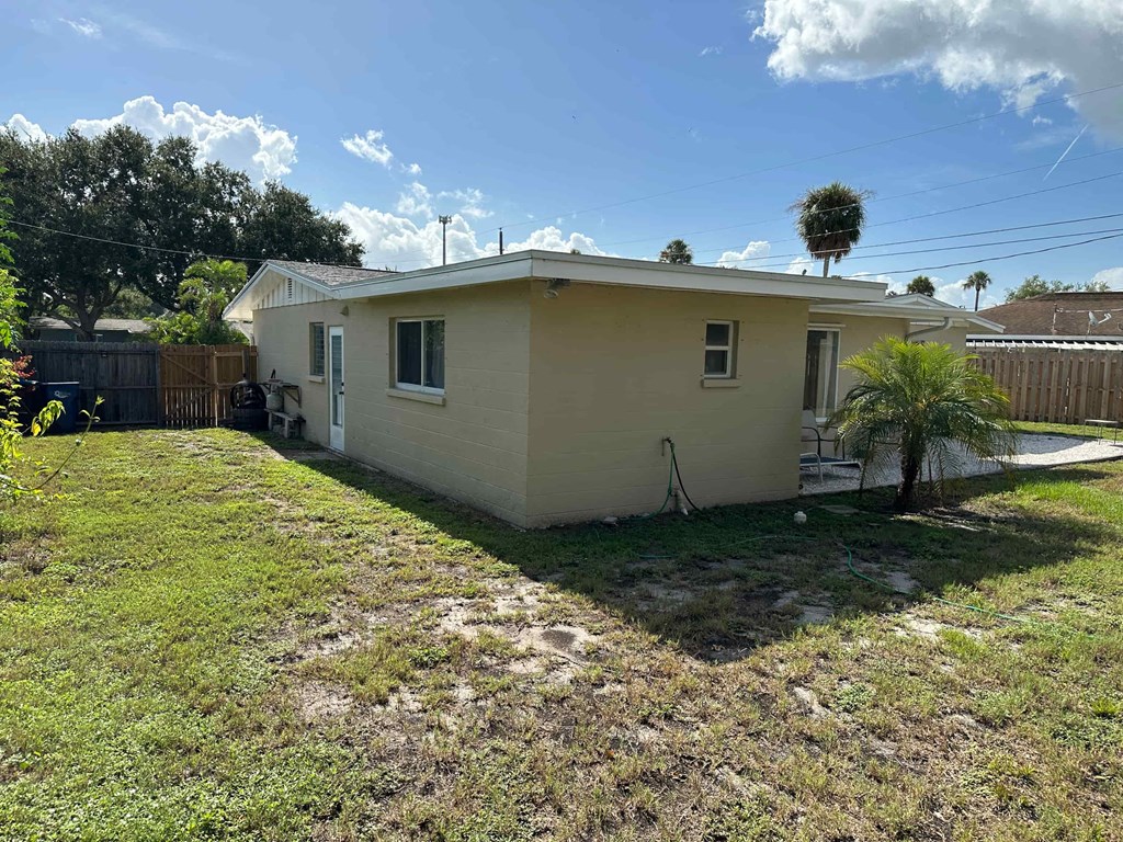 a small house with a yard and a palm tree