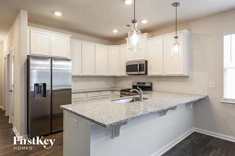 A kitchen with a stainless steel refrigerator and a granite countertop.