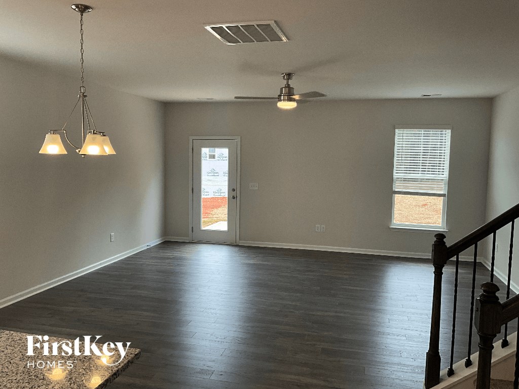 an empty living room with a staircase and a ceiling fan