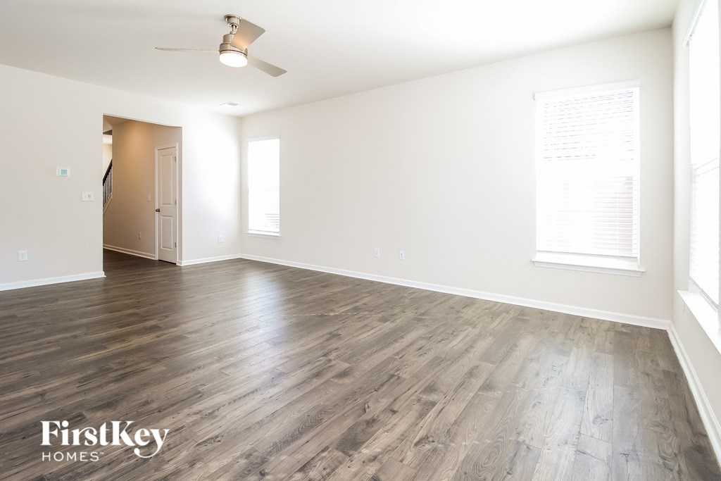 the living room of an apartment with wood floors and white walls
