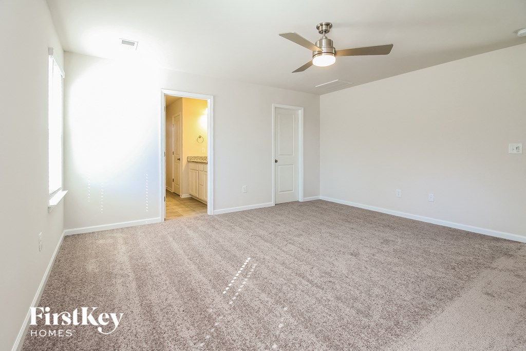 a spacious living room with carpet and a ceiling fan