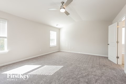 a spacious living room with carpet and a ceiling fan