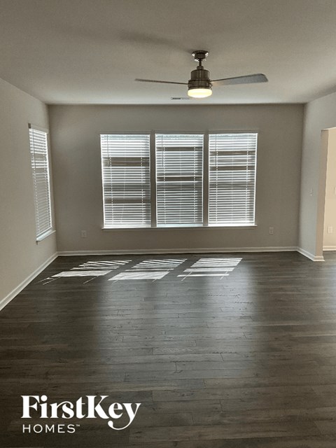 an empty living room with wood floors and a ceiling fan