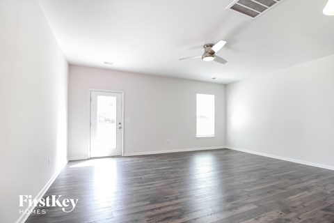A spacious room with wooden floors and a ceiling fan.