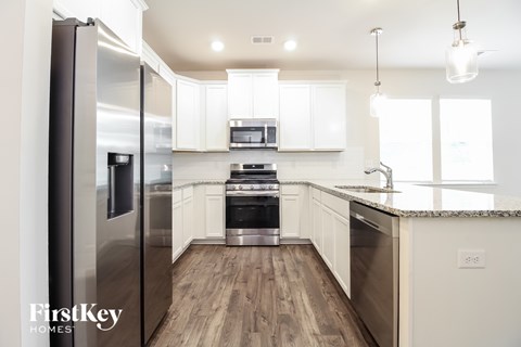 A modern kitchen with a stainless steel refrigerator and wooden flooring.