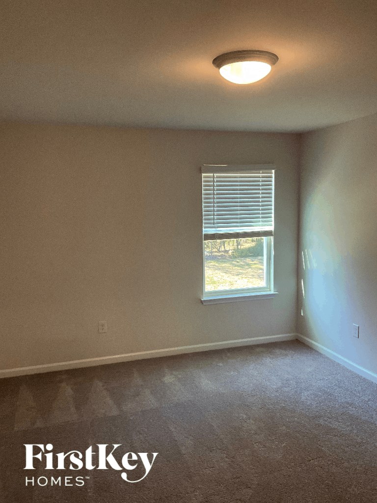 an empty room with a window and a ceiling light
