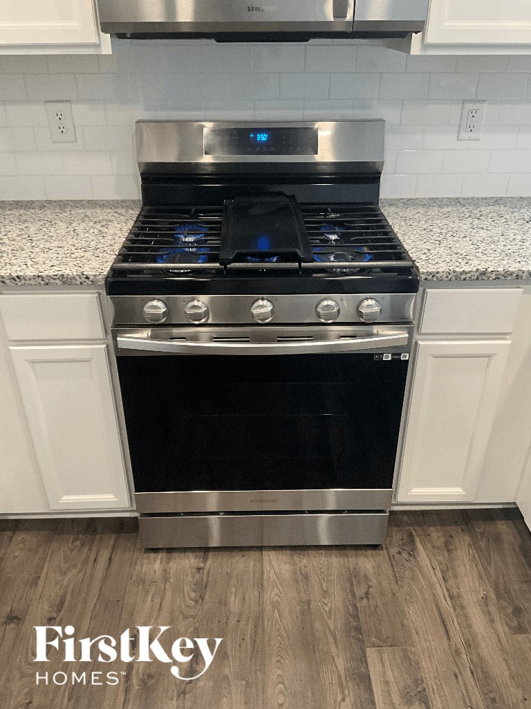 an oven in a kitchen with white cabinets and a counter top