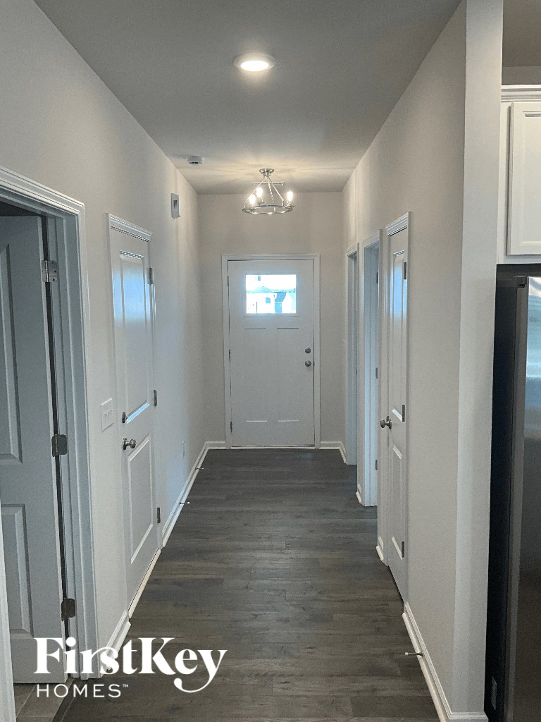 a long hallway with white doors and white walls and a white door with a window