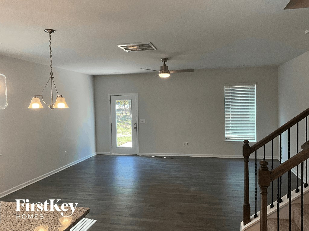 an empty living room with a staircase and a ceiling fan