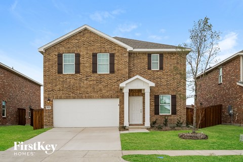 a brick house with a white garage door and a lawn
