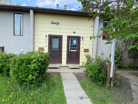 the front of a house with two doors and a sidewalk