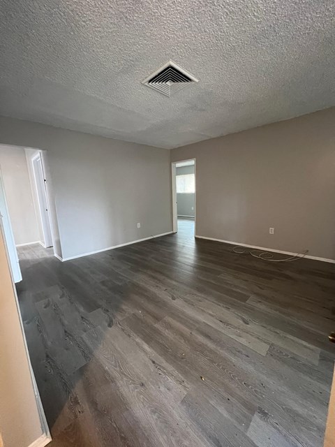 an empty living room with wood flooring and grey walls