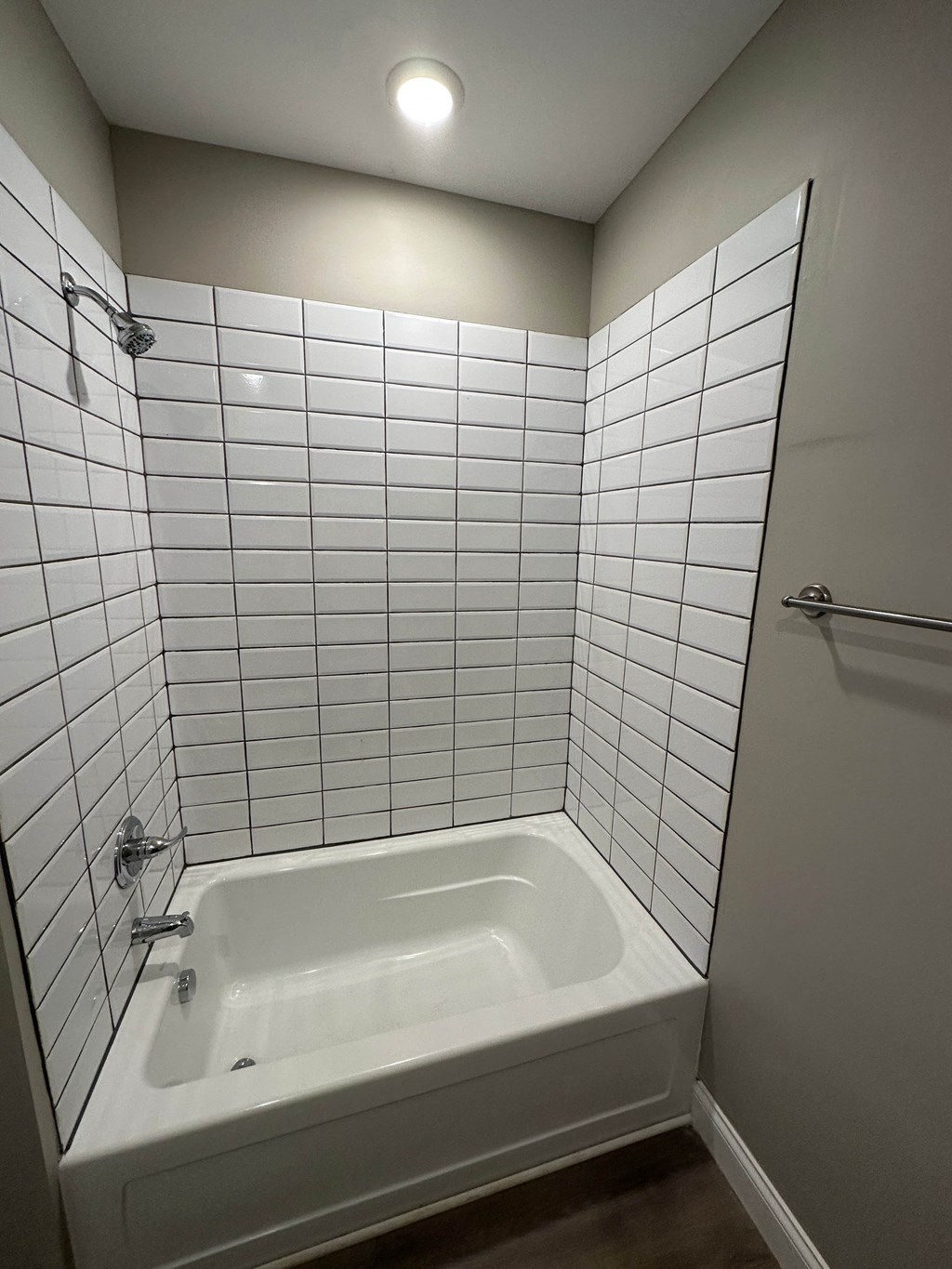 a white tiled bathroom with a tub and a shower
