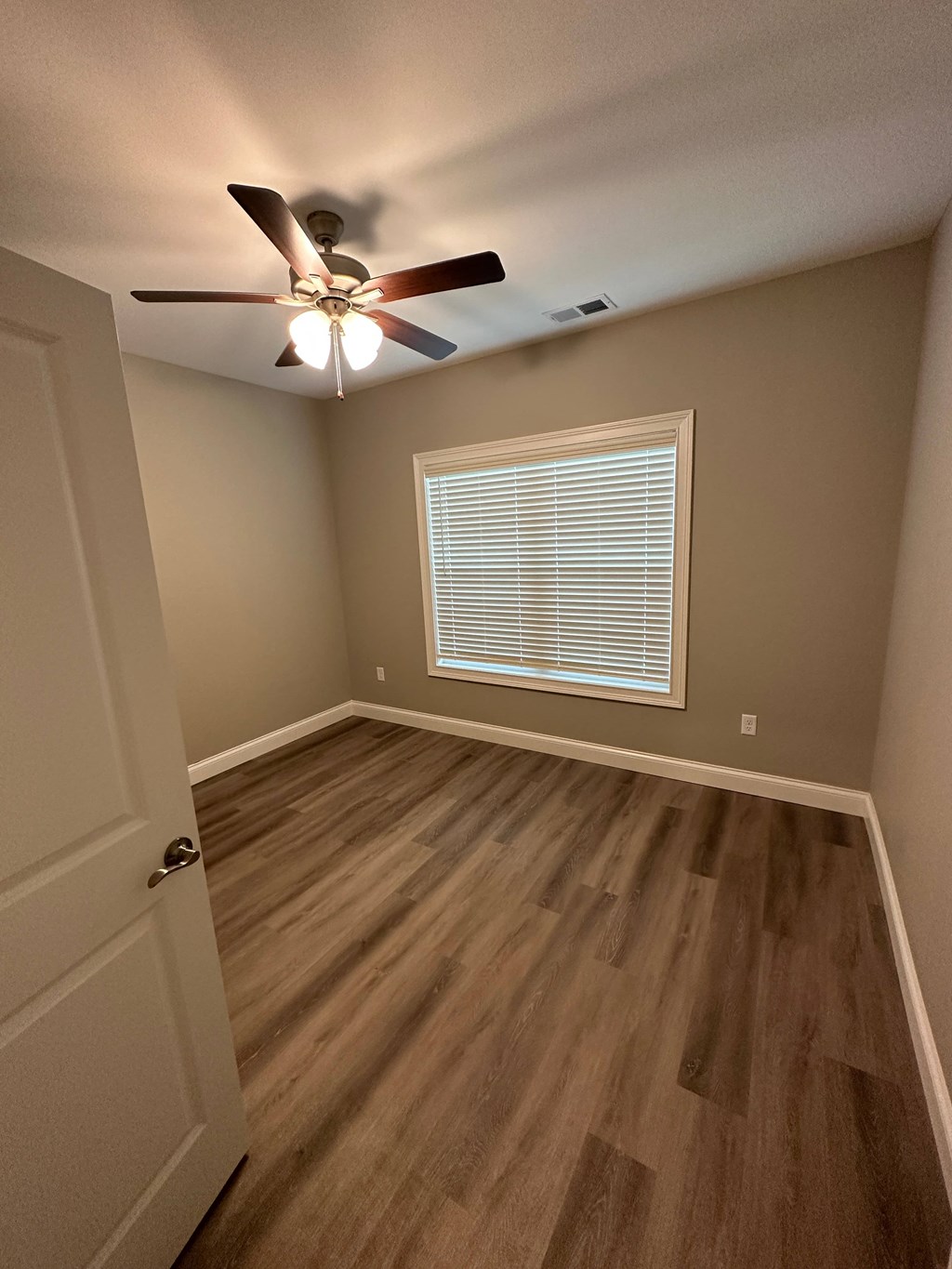 a bedroom with hardwood floors and a ceiling fan