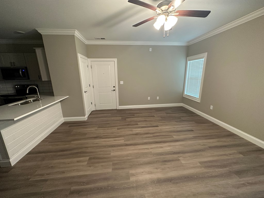 a empty living room with wood floors and a ceiling fan