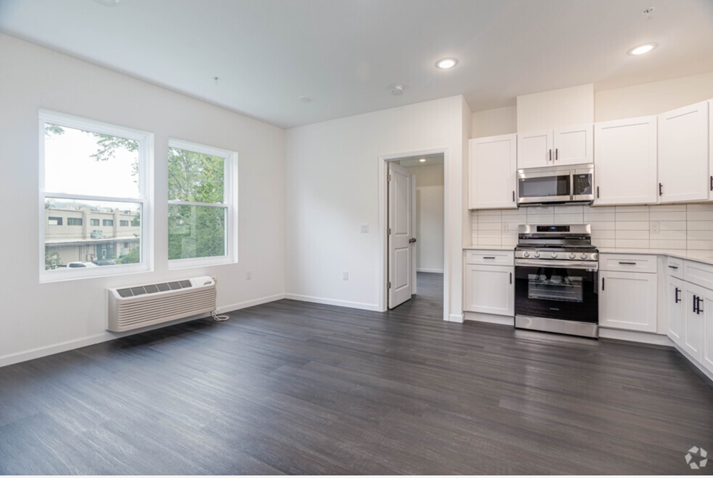 an empty kitchen with white cabinets and stainless steel appliances