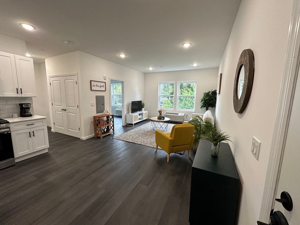 a living room and kitchen with hardwood floors and white walls