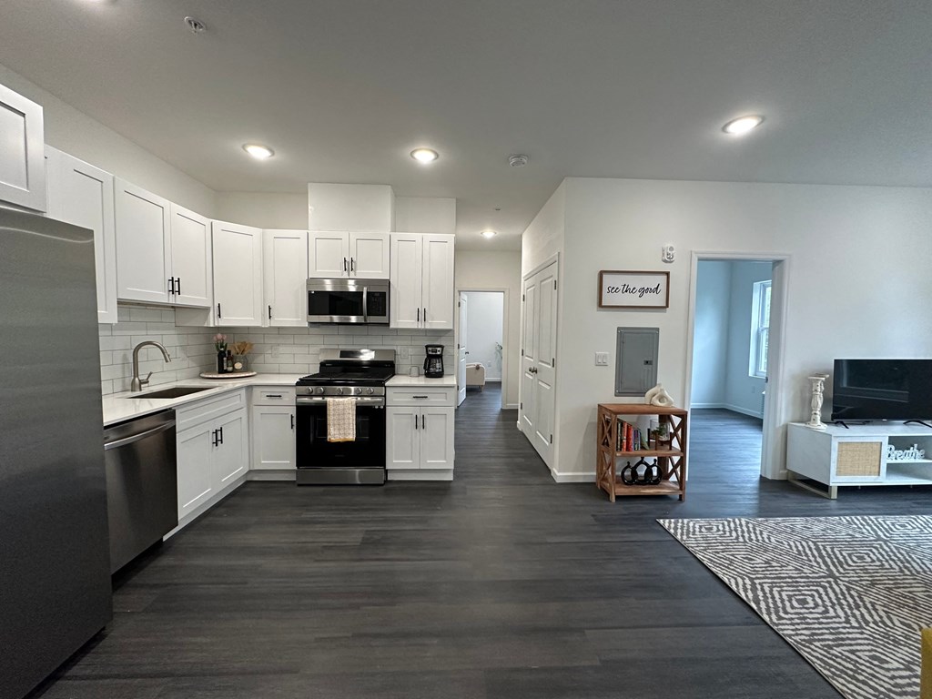 a kitchen and living room with white cabinets and stainless steel appliances