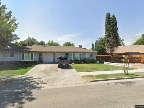 A house with a brown roof and a white car parked in front.