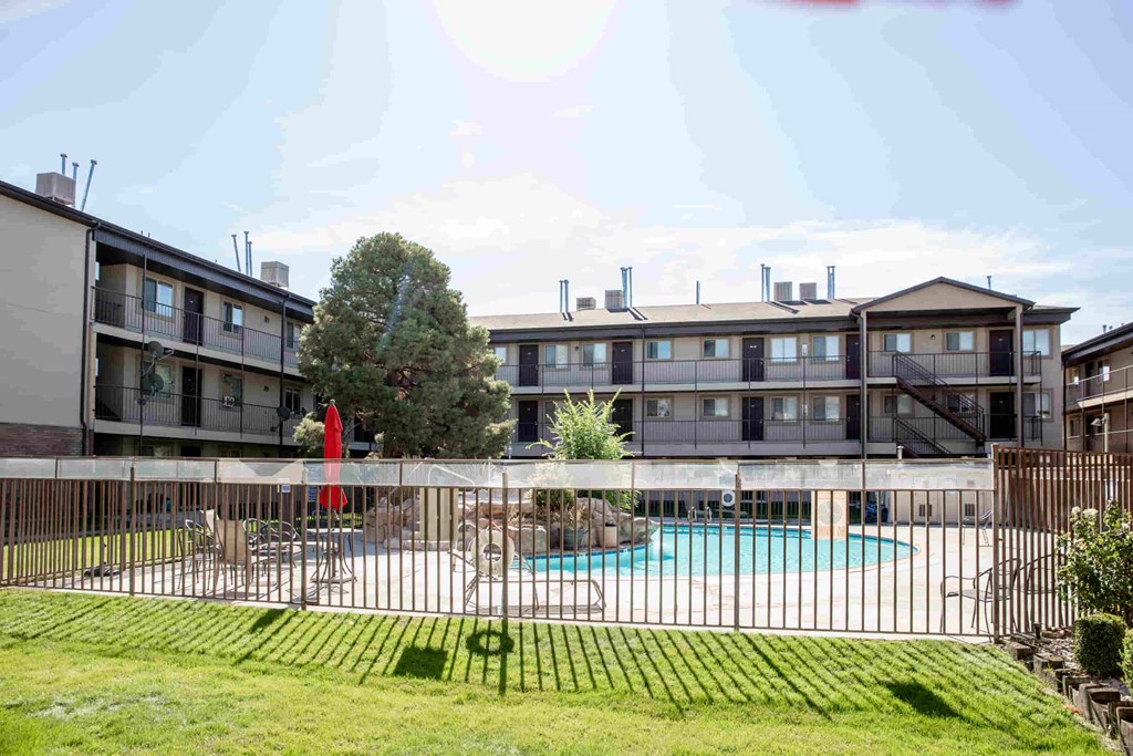 an apartment building with a pool behind a fence