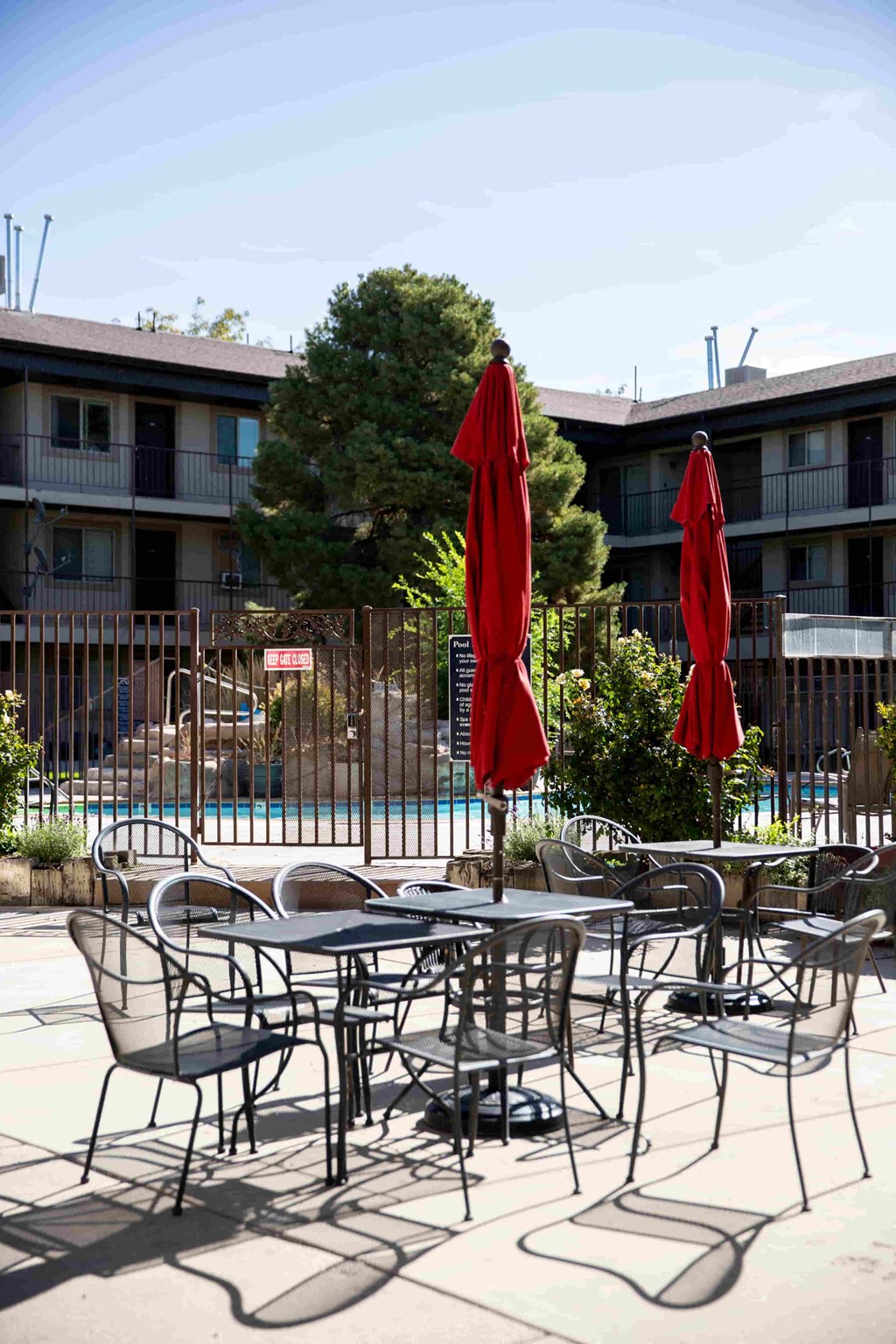 a patio with tables and chairs and umbrellas near a pool