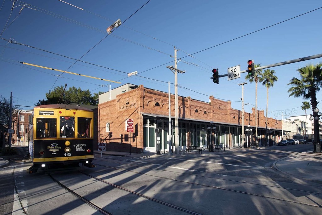 a yellow streetcar traveling down a street in front of a brick building