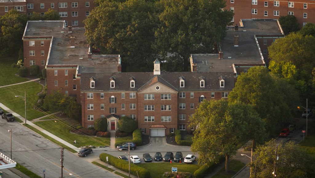 an aerial view of a large building with cars parked in front