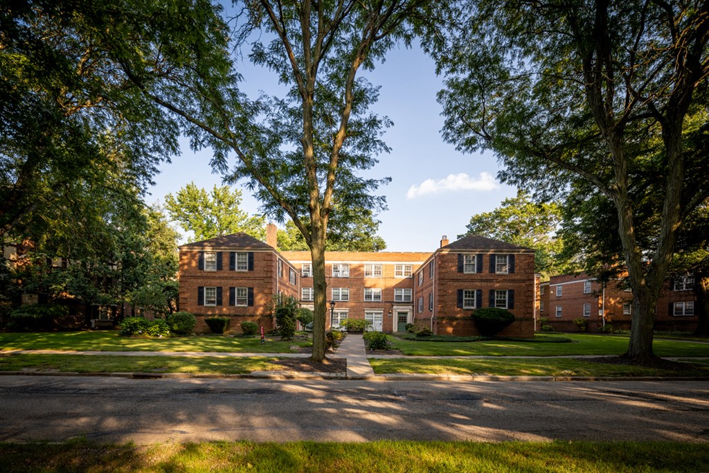 the exterior of a brick building with green grass and trees