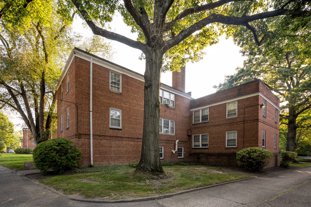 a red brick building with a large tree in front of it