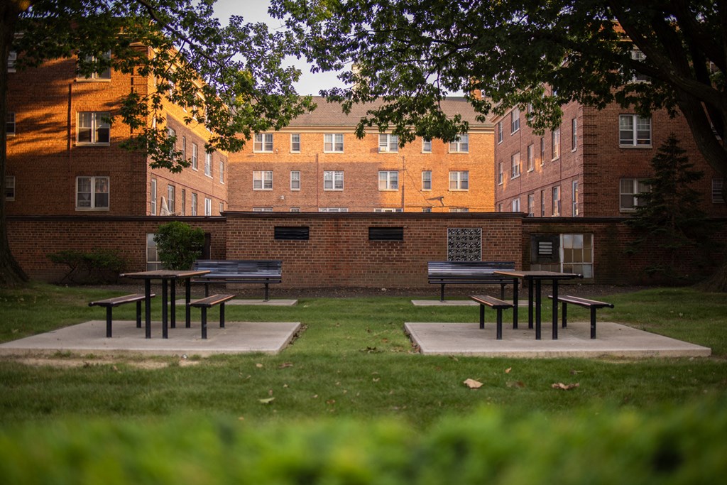 a courtyard with picnic tables and benches in front of a brick building